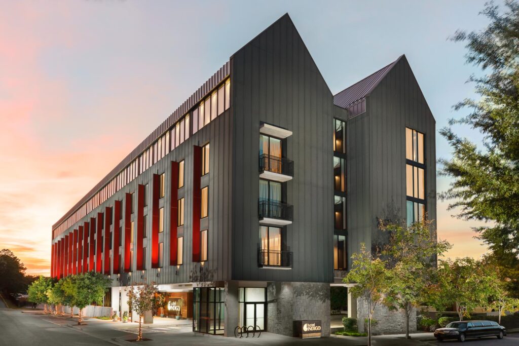 The front of Hotel Indigo pictured in front of a sunset.